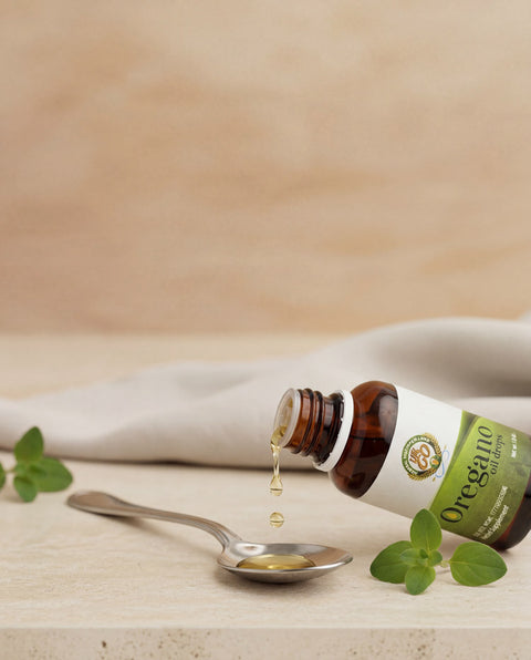 Botella de aceite de orégano líquido OreganicUSA con orifice reducer insert y hojas de orégano en una escena natural y limpia.