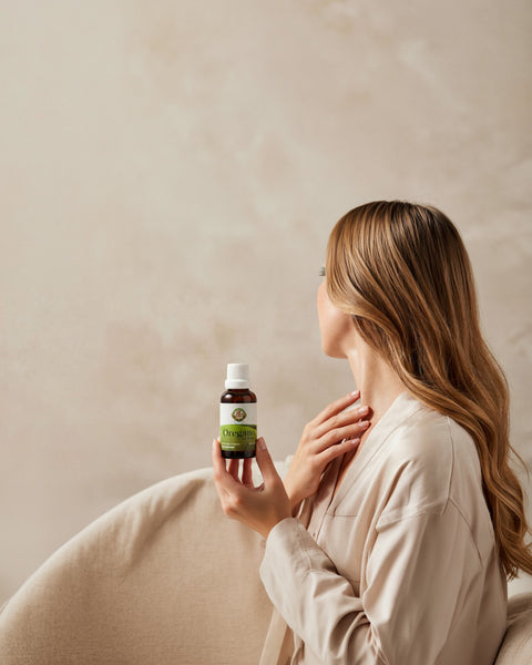 Mujer con cabello hermoso y piel sana sosteniendo una botella de aceite de orégano OreganicUSA con orifice reducer insert en una composición limpia y elegante para móvil.